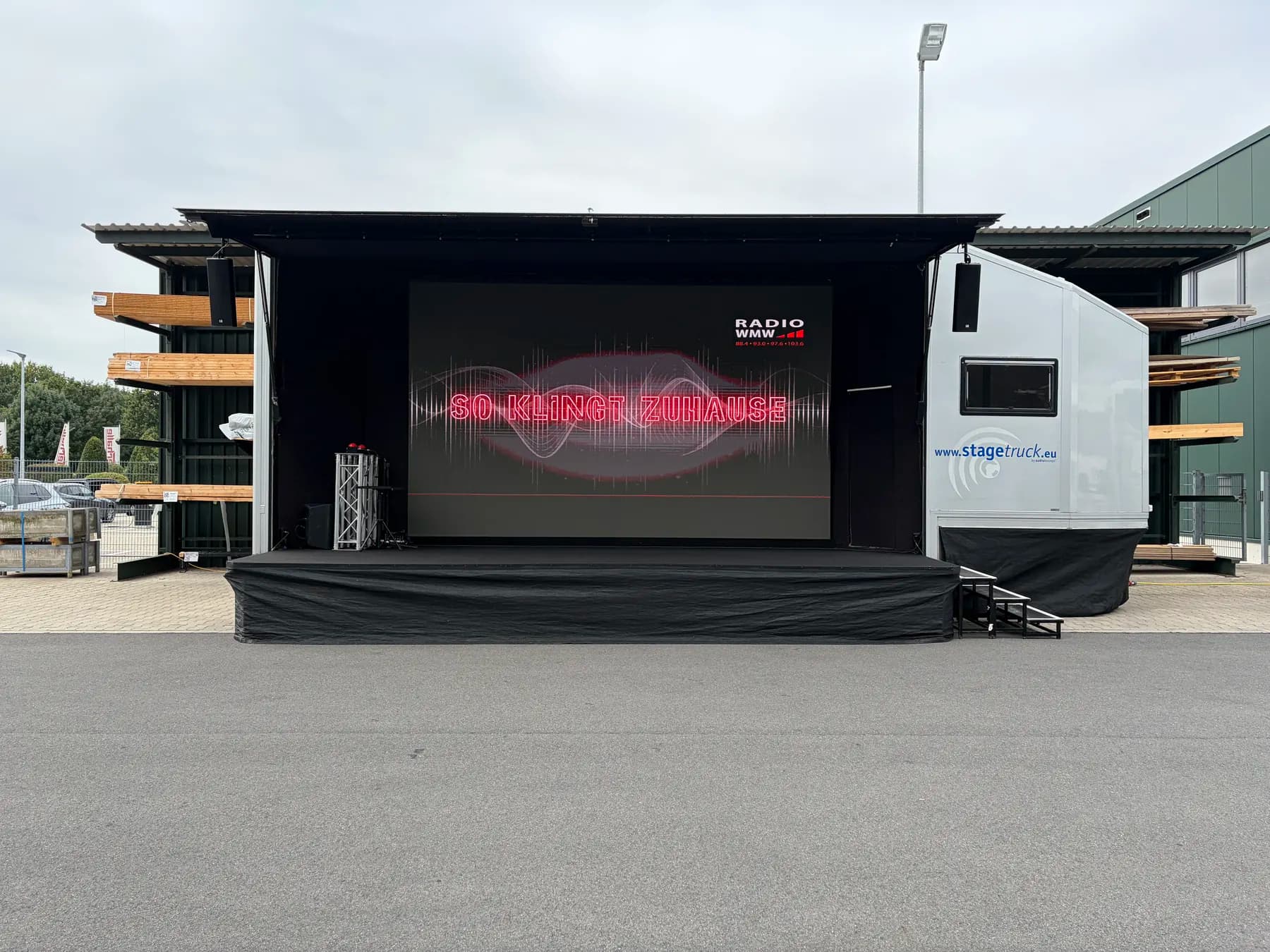 Frontansicht des aufgebauten stagetruck mit großer LED-Wand und Radio-WMW-Motiv auf einem Firmengelände